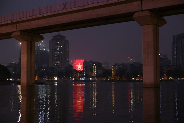 Một tòa nhà trang trí đèn hình lá cờ đỏ sao vàng khổng lồ nhìn từ hồ Hoàng Cầu.